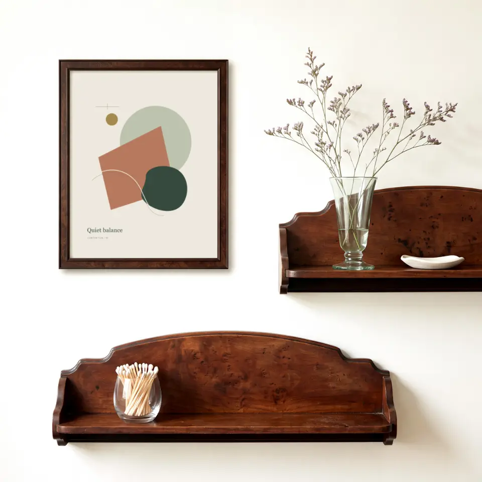 Heirloom Wall Shelves: A slim dark brown frame hangs on a warm white wall beside two scalloped wooden wall shelves, one holding a glass of dried lilac stems and a small dish, the other a tumbler of matches.