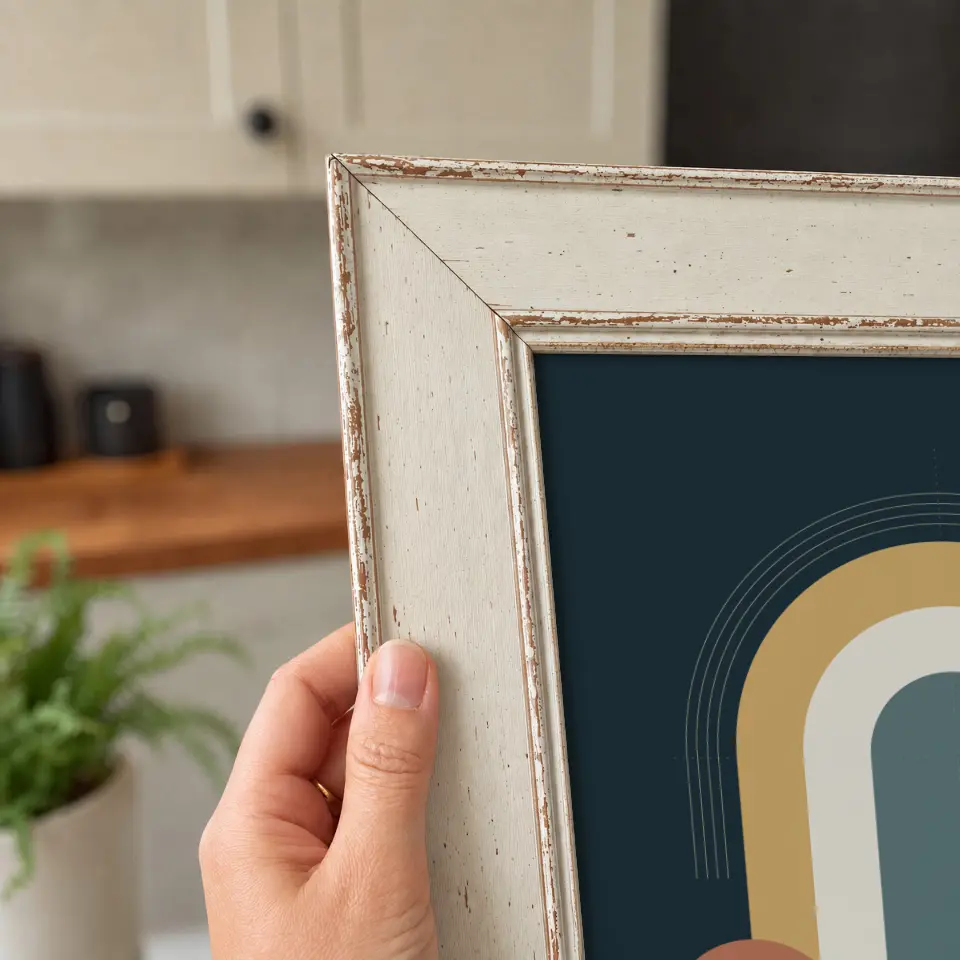 Weathered ivory detail: A close corner view of a weathered ivory wide frame, held in one hand, with chipped paint revealing warm wood beneath the finish.