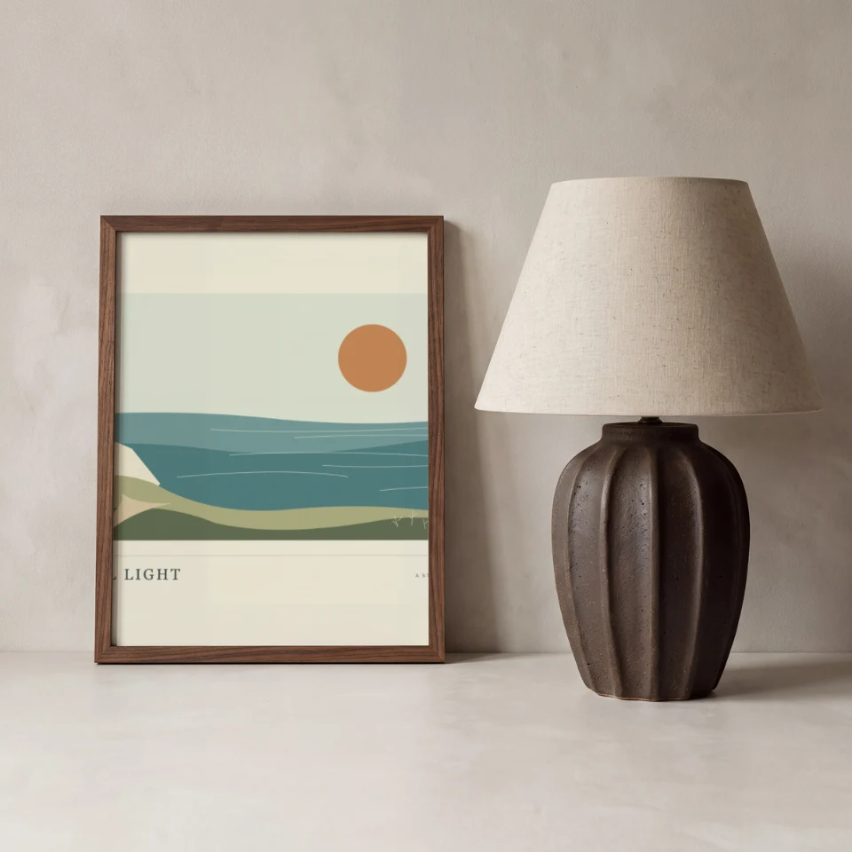Fluted Lamp Rest: Present your artwork in a slim walnut portrait frame leaning on a pale plaster ledge against a soft grey limewash wall.